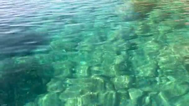 海の水面の質感 太陽の光線の反射 水中の石 青い水 小さな波の動きに太陽が輝いています シーアイドル リラックス バケーション — ストック動画