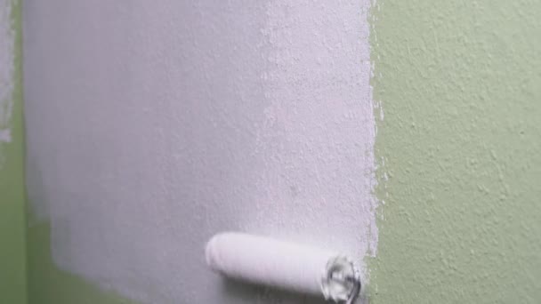 Homem Pinta Uma Parede Verde Com Tinta Branca Usando Rolo — Vídeo de Stock