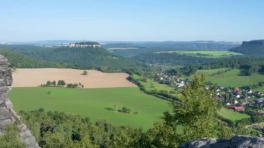 Almanya 'daki Sakson İsviçre Ulusal Parkı' ndaki muhteşem bir kırsal arazinin uçurumundan görüntüler. Yeşil, yemyeşil çimenler, güzel evler, güçlendirilmiş Knigstein kalesi, güneşli bir gün.