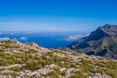 Mallorca 'nın muhteşem manzaraları. Dağlar yeşillikle kaplı, deniz mavi ve şeffaf. Güneşli bir gün, kayalık bir tepenin üzerindeki bulutlar. Mallorca, İspanya, Balear Adaları