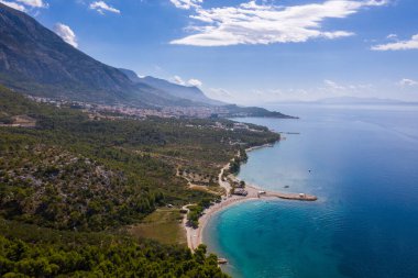 Hava aracı görüntüsü. Güzel sahil şeridi, denize giden beyaz iskele, mavi deniz. Makarska Avrupa 'da ünlü bir turistik yerdir. Hırvatistan 
