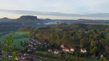 Almanya 'nın Dresden yakınlarındaki Sakson İsviçre' nin ulusal parkındaki uçurumdan güzel bir manzara. Aşağıda rahat evler var. Lilienstein Dağları ve Knigstein Kalesi 'ne