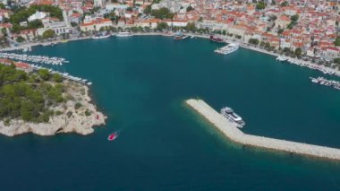 Güzel bir kıyı şeridi, turistli bir körfez, limanda demirli gemiler ve yatlar ve dağların manzarası. Hırvatistan 'ın Makarska Riviera kentinde sakin plaj ve geleneksel tekneler.