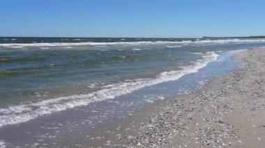 Bir dalga kumlu plaja doğru yavaşça yuvarlanıyor. Baltık Denizi. Almanya