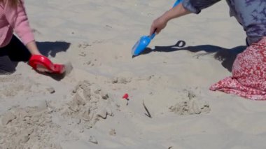 Bir kadın ve tatlı bir kız denizde tatilde eğleniyorlar. Büyükanne ve torun kumsalda oynuyorlar. Bir kule inşa ediyorlar. Ağır çekim. Baltık Denizi. Almanya