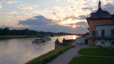 23.06.2024. Dresden, Saksonya, Almanya. Bir turist gemisi gün batımında Elbe Nehri boyunca yavaşça yelken açar. Güzel Pillnitz Sarayı 'nın yanından geçiyor. Turistler gün batımının ve manzaranın tadını çıkarırlar. Turizm ve dinlenme