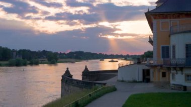 Feribot, insanları nehrin bir tarafından diğerine taşıyor. Nehirde gün batımı. Batan güneş ışınları nehre düşer. Dresden, Pillnitz Sarayı, Elbe Nehri, Almanya