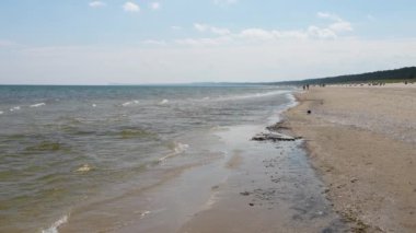 Baltık Denizi kıyısında. Kuzey Denizi kumlu sahile hücum ediyor. Karga sahile kadar yürür. Turistler tatillerini denizde geçiriyorlar. Baltika, Almanya