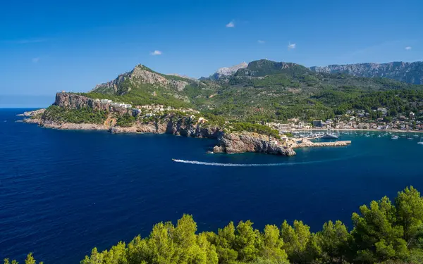 Bir turist teknesi hızla kıyı şeridini geçiyor. Port de Soller 'in panoramik manzarası, Palma Mallorca, İspanya. Mallorca 'da popüler bir turizm merkezi.