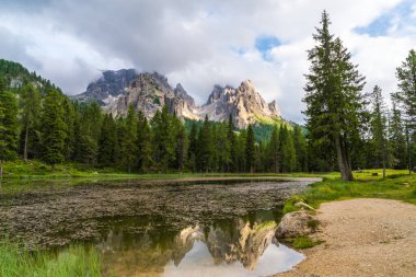 Dolomitlerin manzarası çok güzel. Görkemli dağlar bulutlarda gizlidir. Kayalar küçük bir göle yansıyor. İtalya, Güney Tyrol. Avrupa turizm beldesi