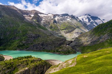 Karla kaplı tepelerden, yeşil çimlerle kaplı dağlardan ve mavi gölden oluşan huzurlu bir manzara. Grossglockner, Avusturya 'nın en yüksek dağı. Hohe Tauern Ulusal Parkı 
