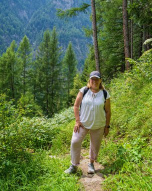 Mutlu orta yaşlı kadın Alp dağlarının güzelliğinin tadını çıkarıyor. Sırt çantasıyla kısa bir yürüyüşe çıkmak. Gülümsüyor ve kameraya bakıyordu. Yaşam biçimi.