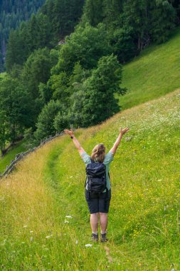 Sırt çantasıyla dağlarda yürüyüş yapan neşeli bir kadın. Ellerini kaldırdı. Arkadan bak. Güzel dağ manzarası. Orta yaşlarda seyahat etmek. Grossglockner. Hohe Tauern Ulusal Parkı, Avusturya 