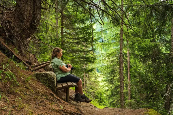 stock image Woman resting on a wooden bench during a hiking trip. Hohe Tauern National Park in the Alps in Austria. Hiking wooden route. Hiking, tourism, travel. High quality photos 