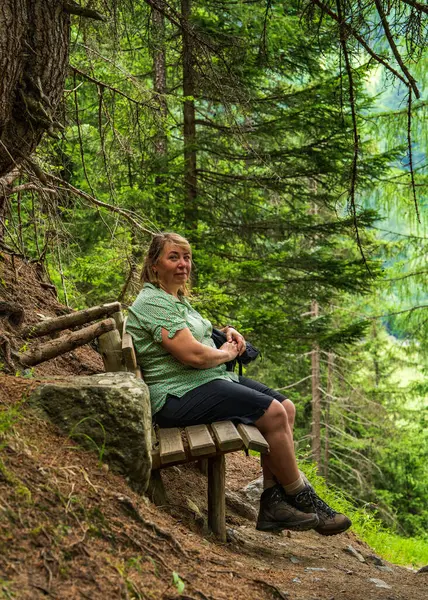 stock image Woman resting on a wooden bench during a hiking trip. Hohe Tauern National Park in the Alps in Austria. Hiking wooden route. Hiking, tourism, travel. High quality photos 