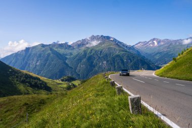 Yalnız bir araba yılan gibi bir dağ yolunda koşuyor. Resimli dağlar bulutların içinde gizlidir. Bulutlardaki yüksek dağlar. Grossglockner High Alpine Yolu, Avusturya. Yüksek kalite fotoğraf