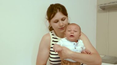  Genç anne yeni doğmuş oğlunu kollarında tutuyor. Annesi onu okşar, yeni doğmuş bebeğini öper. Anne sevgisi ve özen, şefkat.  