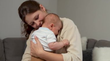Anne ve yeni doğmuş bebek. Mutlu anne kucağında yeni doğmuş oğlunu öpüyor, sarılıyor. Annelik kavramı. Ebeveynlik. Mutlu bir aile. Yavaş çekim