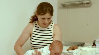 Yeni doğmuş bebeği kucağında tutan mutlu bir anne. Anne nazikçe öpüyor ve ağlayan bebeği sakinleştiriyor. Mutlu annelik kavramı. Anne ve bebek. Yavaş çekim 