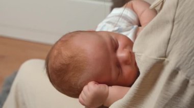 Anne şefkatle kucağında uyuyan yeni doğmuş bebeği tutuyor. Bebek mışıl mışıl uyuyor. Bebek suratını kapat. Anne ve yeni doğmuş bebek, mutlu annelik 