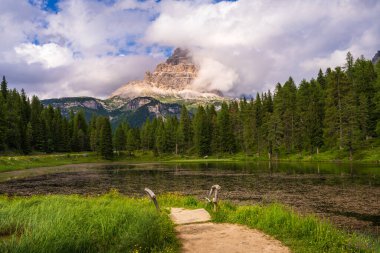 Ünlü dağlardan oluşan eski ahşap bir köprüye bakın. Drei Zinnen ya da Tre Cime di Lavaredo kalın bulutların arkasından pek görünmüyor. Dolomite Alpleri 'nin dağ manzarası. 