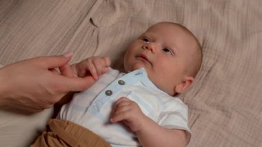 Annelerin elleri nazikçe bebeklerin elini tutar. Yeni doğan bebek annesine bakıyor. Bebek yüzlü kostüm 