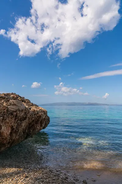  Açık deniz için geniş kayaların ötesine bakın. Güneşli bir gün. Mavi gökyüzünde büyük bulutlar. Hırvatistan.