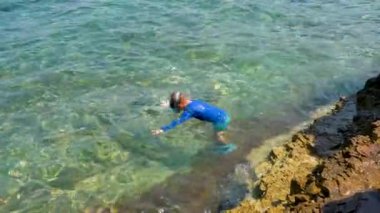  Çocuk denize dalıyor. Çocuk yüzmeyi ve dalmayı seviyor, kafasını suya sokuyor, dalgalarla oynuyor, eğleniyor. Yaz günlerinin tadını çıkar. Mutlu çocukluk .