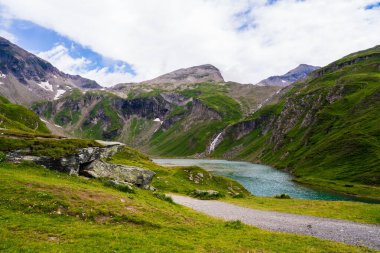Dağ zirvelerinin arasında küçük gölü olan güzel bir vadi, çağlayan bir şelale. Doğanın güzelliği. Grossglockner High Alpine Yolu. Avusturya