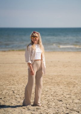 Baltık Denizi 'ndeki beyaz kumsalda mutlu genç bir kadın. Zevk, duygular, tatil