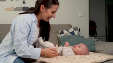 Sevgi dolu anne yeni doğmuş bebeğiyle konuşuyor. Bebek yatakta yatıyor. Mutlu anne, sevginin ve şefkatin tadını çıkar. Ebeveynler ve çocuklar arasındaki bağ, annelik bakımı