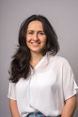 Beyaz gömlekli, gülümseyen beyaz bir kadın. Kameraya bakıyorum. Işık arka planında izole edilmiş. Stüdyo portresi. Yaşam tarzı kavramı