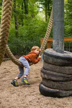 Çocuk dışarıda eğleniyor. Çocuk salıncakta sallanıyor parkta.