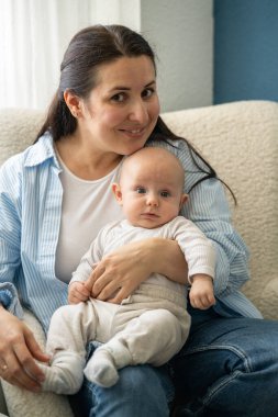 Annesinin kucağında oturan tatlı bir bebek.