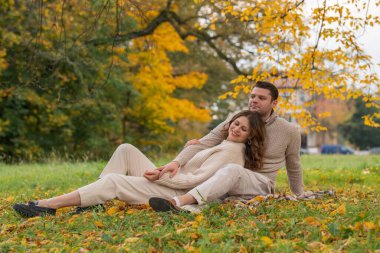 Birbirine aşık bir çift, güz parkında otururken birbirini nazikçe kucaklıyor. Romantik ilişki.