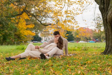 Birbirine aşık bir çift, güz parkında otururken birbirini nazikçe kucaklıyor. Romantik ilişki.