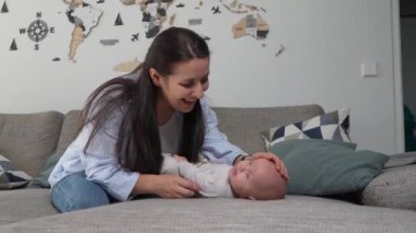 Neşeli anne bebeğiyle yatakta oynuyor, bebeği öpüyor. Mutlu annelikler. Yeni doğan bebeğe bakıyorum.