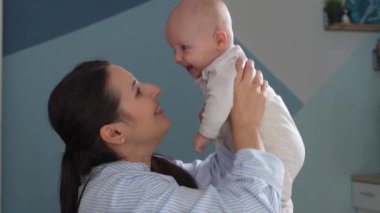 Gülen, mutlu bir kadın bebeğiyle evde oynuyor..