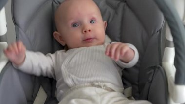 Sallanan sandalyede yatan yeni doğmuş şirin bebek. Mutlu bebek sabahları, bebek aktiviteleri.