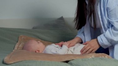 Gülen anne, evde birlikte vakit geçirmek için komik bebekle oynarken tatlı bebekle dikkatlice konuşur. Sevgi dolu anne sevgili bebeğin karnını okşuyor. 