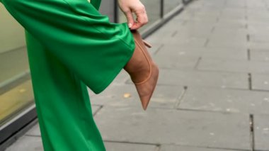  Şık yeşil takım elbiseli genç bayan ayakkabısını nazikçe düzeltiyor. Ayrıntılara odaklan, yüzünü göstermeden, zarif bir stil yayarak. Moda ve iş konuları için mükemmel