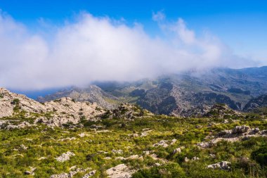 İspanya 'nın Mallorca adasındaki görkemli Tramuntana Dağları. Dik yamaçlı manzara, yeşil vadiler. Mavi gökyüzü, bulutlar doğal güzelliği vurgular. Seyahat, doğa, macera