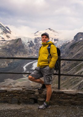 Orta yaşlı adam Grossglockner Dağı ve Hohe Tauern Ulusal Parkı 'ndaki Pastersee Buzulu' na bakan gözlem güvertesinde duruyor. Konsept: seyahat, açık hava aktiviteleri.