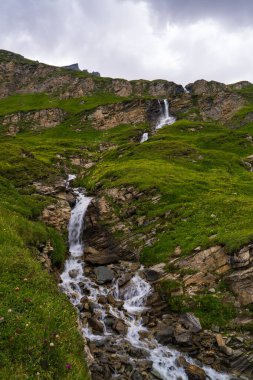 Avusturya Alpleri 'ndeki ünlü Grossglockner Hochalpenstrasse yüksek dağ yolu boyunca akan şelale. Yol Hohe Tauern Ulusal Parkı 'ndan geçiyor. Resimli görünüm.