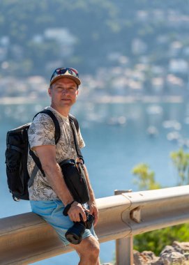Profesyonel kameralı seyahat fotoğrafçısı taş çitin üzerinde oturur ve Port de Soller of picorresque Mallorca 'nın deniz manzarasının tadını çıkarır. Fotoğraf, seyahat, yaratıcı keşif..