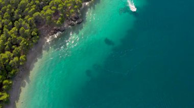 Tatilcilerle dolu hava manzaralı bir sahil. Turkuaz su kıyıları yıkar. Sürat teknesi açık denizde yelken açar. Makarska, Hırvatistan ve Dolmacia. 