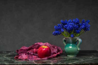 Minimalist bahar, mermer masa üzerindeki küçük vazoda narin mavi muscari çiçekleriyle sakin bir hayattır..