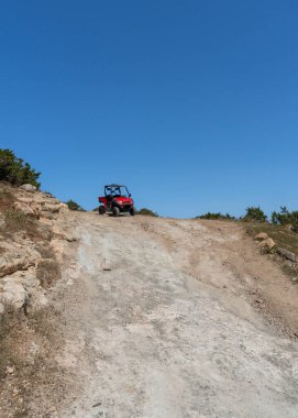 Parlak güneşin altında toprak yolda bir arazi aracı ve Kıbrıs 'ta açık bir gökyüzü. Güzel güneşli bir günde açık hava meraklıları için popüler macera etkinliği.