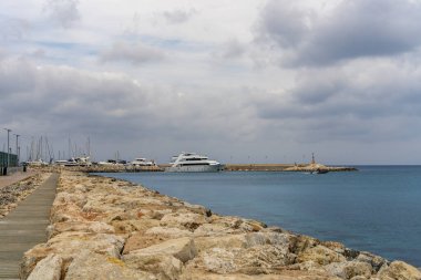 Kıbrıs, Latchi 'de açık renkli taşlarla güzel bir gezinti alanı. Rahatlama, seyahat etme, deniz kenarında eğlenme kavramı.