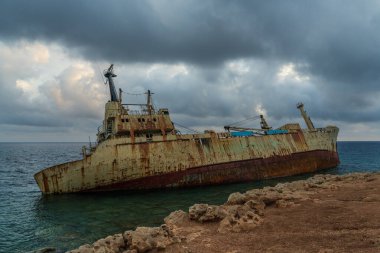 Kayalık sahil kenarındaki eski gemi enkazı güzel günbatımı gökyüzüne karşı. Sistemin kıyısında. Turistik eğlence ve deniz manzarası.